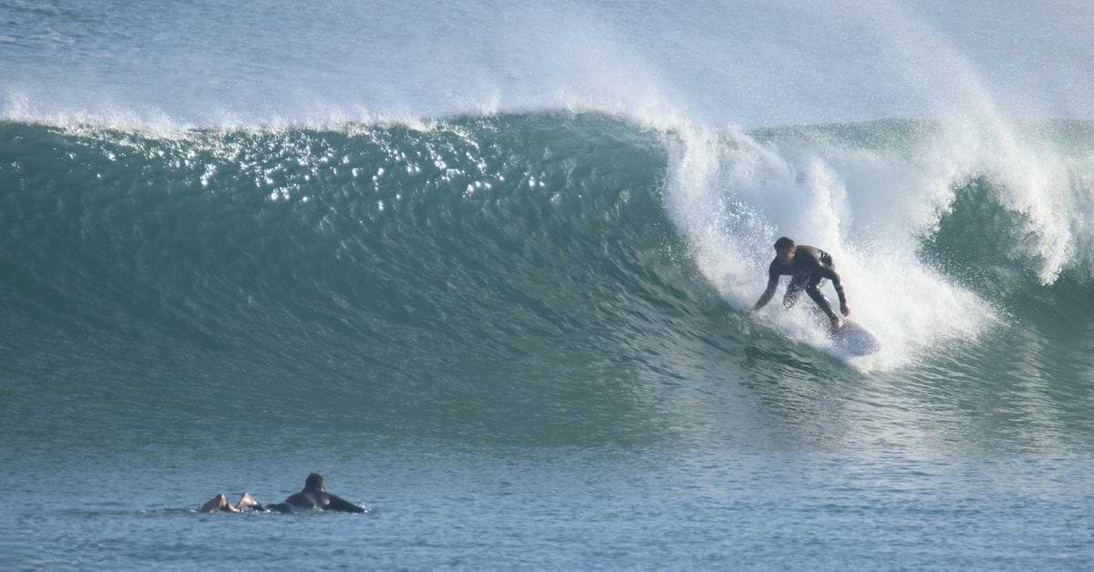 Surfer dropping into a hollow green wave in Peniche, Portugal.