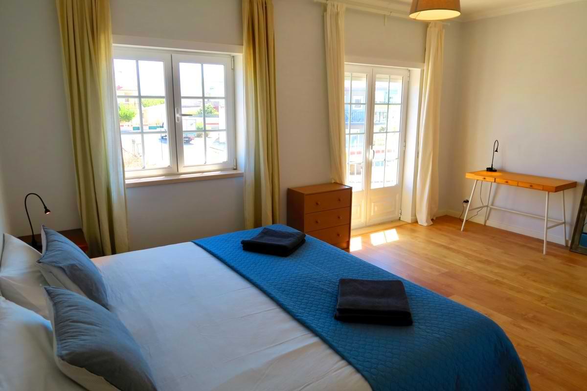Large double bedroom at Chillax Villa featuring a wooden writing desk, chest of drawers, and double doors opening to natural light