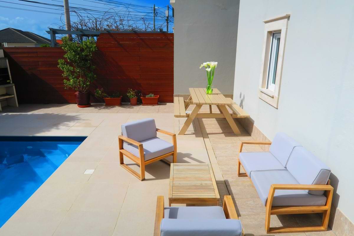 Elevated view of the poolside patio furniture setup at Chillax Villa, including the outdoor sofa, armchairs, coffee table, and wooden bench.