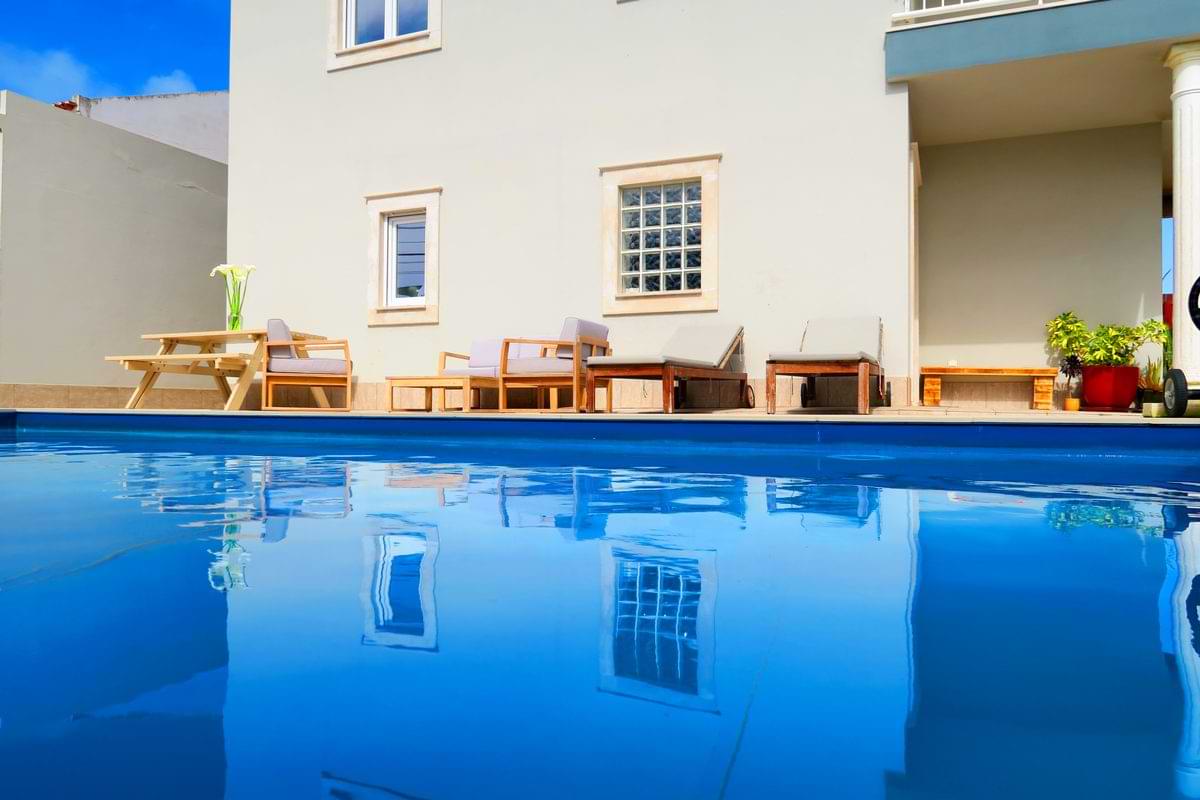 Exterior facade of Chillax Villa with sun loungers and crystal clear water reflecting the house.