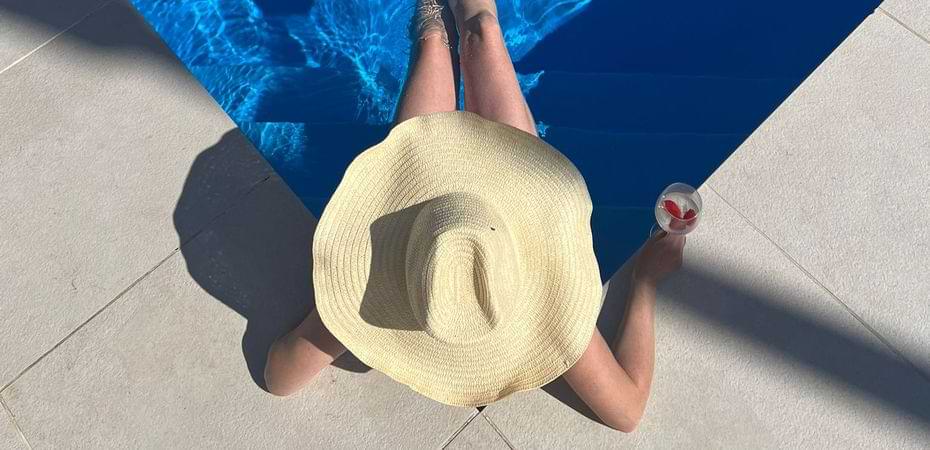 cta-chillax-villa Person relaxing by pool with hat and drink