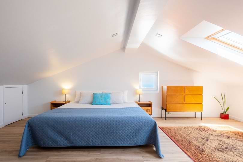 Surf Atlantic Premium Bedroom Suite Spacious attic bedroom with a king bed, skylight, and modern wooden decor at Surf Atlantic surf house in Baleal.