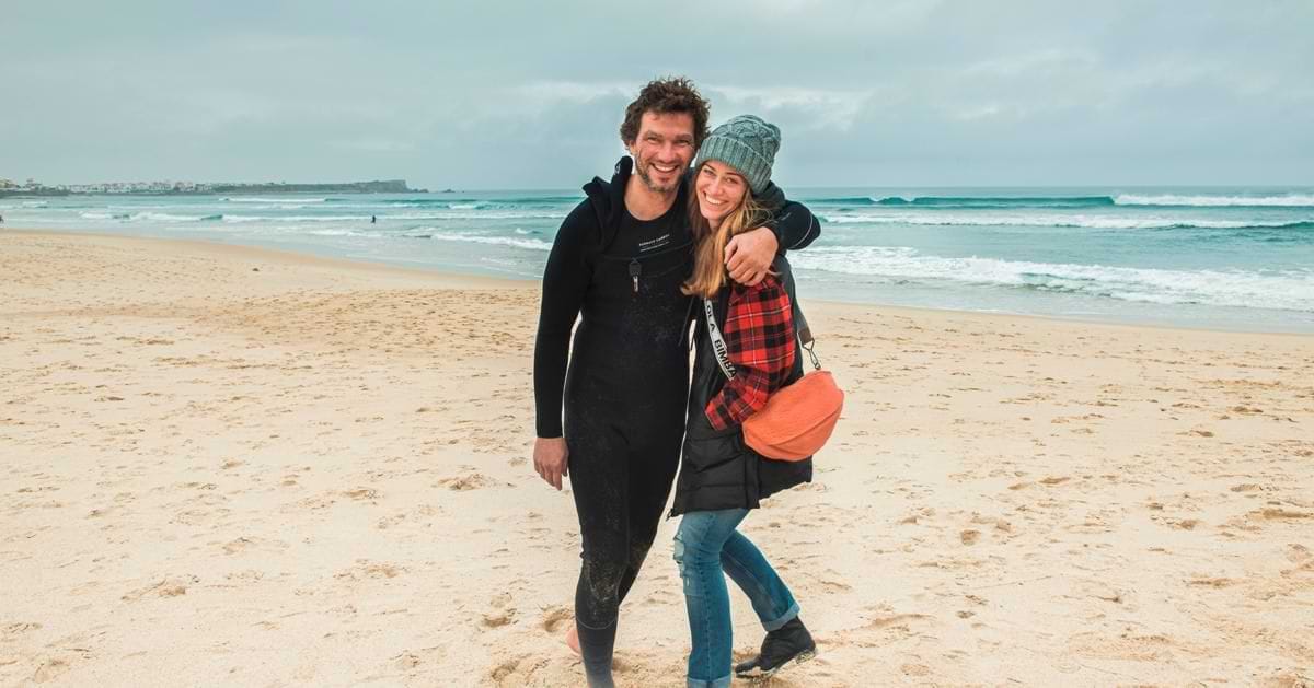 Zuzana and Tibor hugging on the sandy beach in Baleal, Portugal, next to the ocean waves.