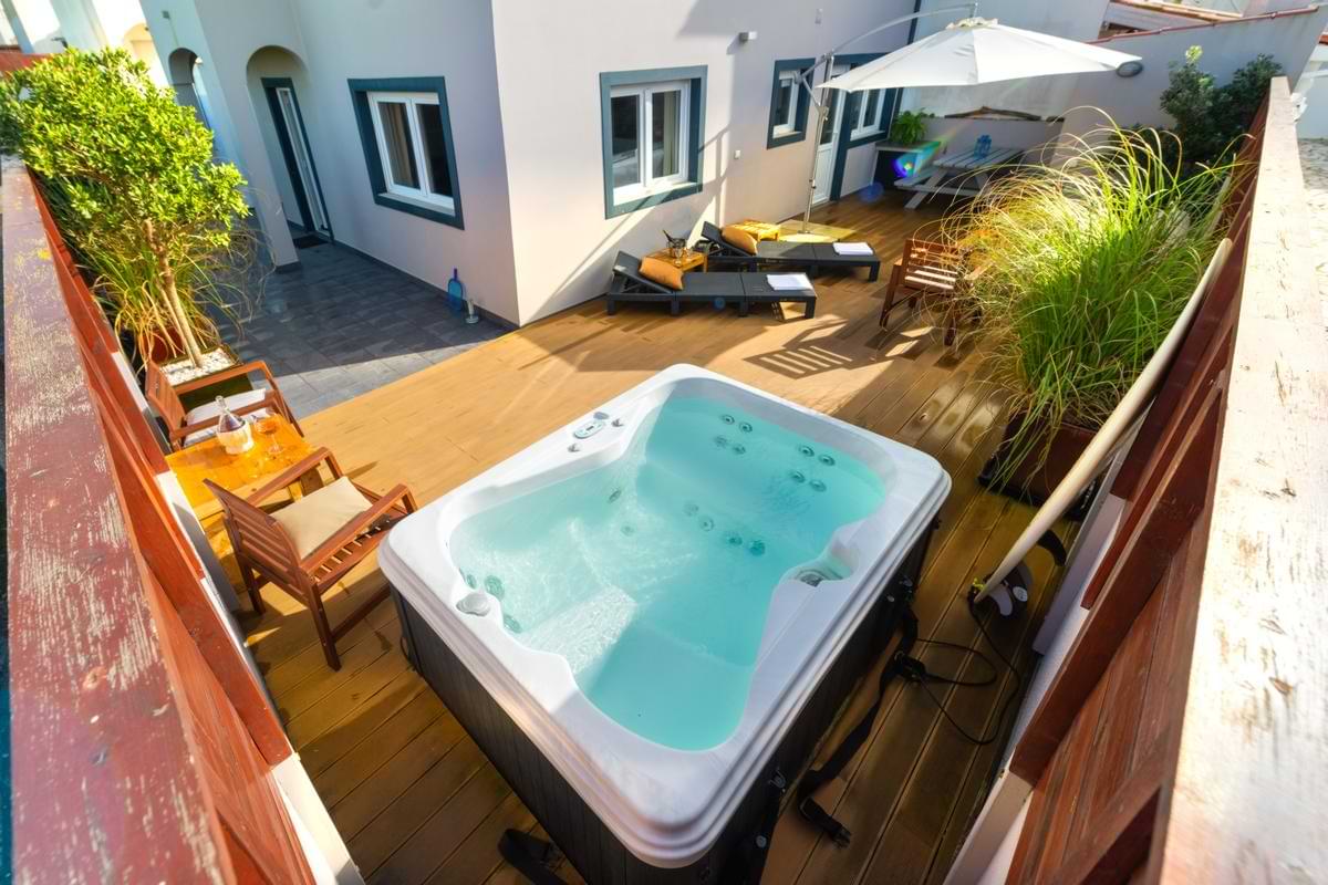 High-angle vantage point showing the hot tub, outdoor sun loungers, parasol umbrella, and back patio area of the Surf Atlantic property.