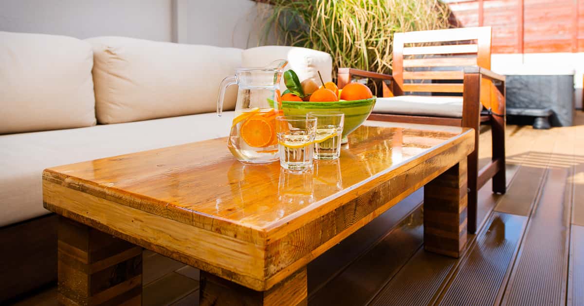 Varnished wooden coffee table with fruit and citrus water on an outdoor terrace lounge at Surf Atlantic surf house.