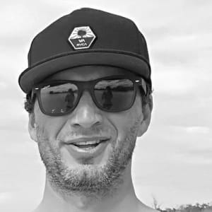 Tibor - Co-Founder of Surf Atlantic House Black and white portrait of Tibor, co-founder of Surf Atlantic, wearing a cap and sunglasses smiling.